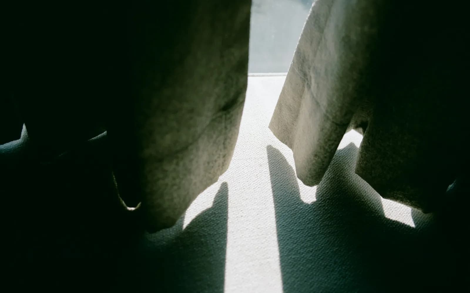 Sunlight streams through parted curtains casting shadows