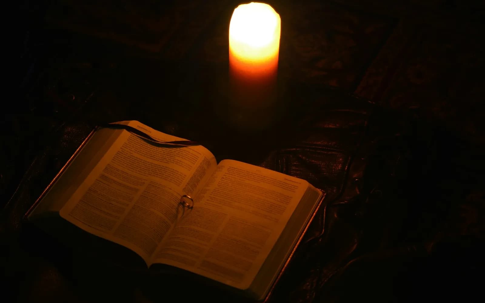 A lit candle illuminates an open book